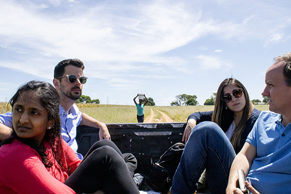 Growth Lab researchers seated in the back of a vehicle traveling through rural Namibia as a women walks in the distance.