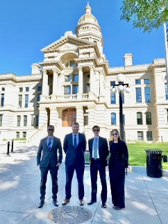 Dressed in formal business attire, four Growth Lab researchers stand in front of the Capitol Building in Cheyenne, Wyoming.