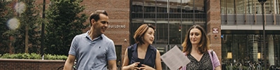 Three students walking through the HKS courtyard.