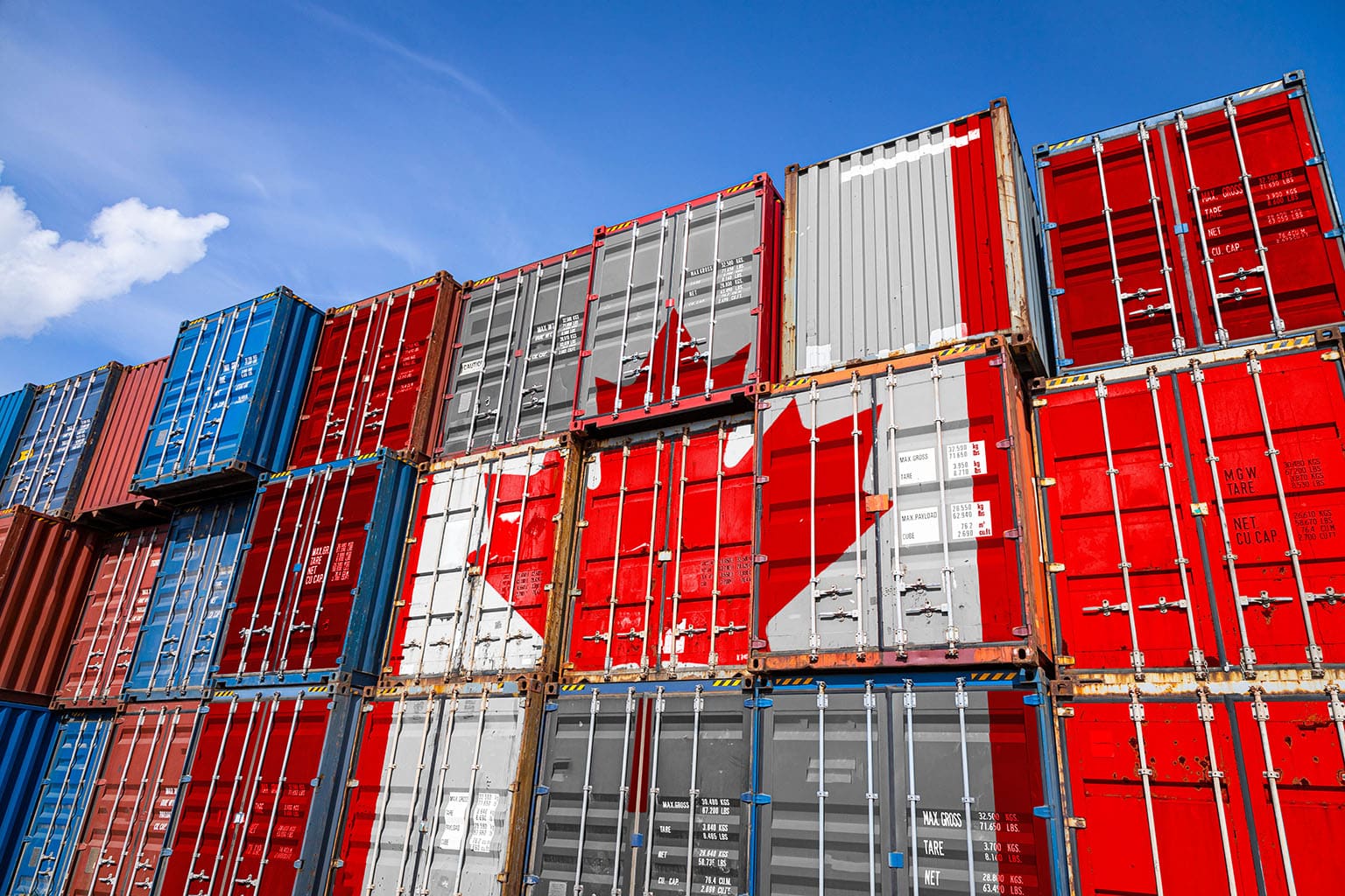 The national flag of Canada on a large number of metal containers for storing goods stacked in rows on top of each other.